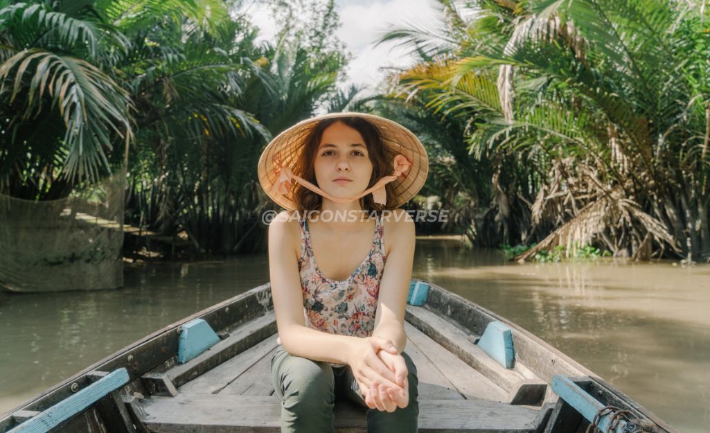 Tourists rowing a sampan boat through shaded canals in Ben Tre