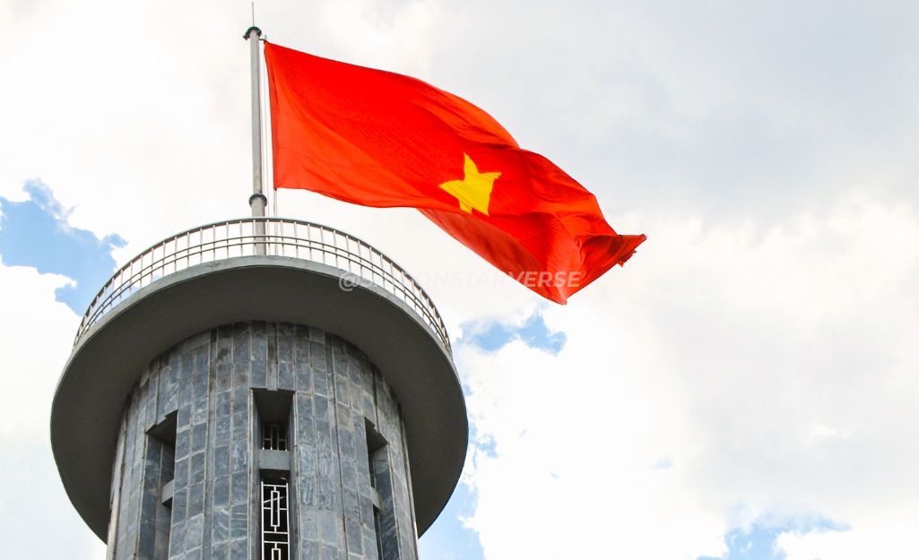 Bức ảnh chụp từ cột cờ Lũng Cú, với lá cờ đỏ sao vàng tung bay trên nền núi non hùng vĩ.