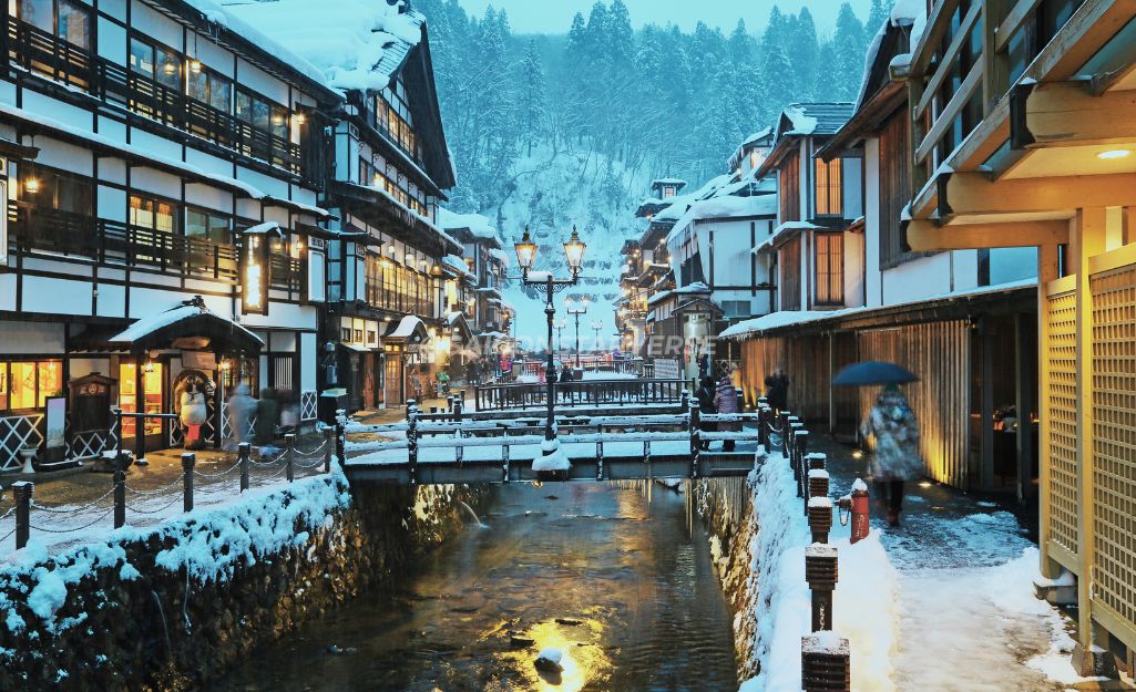 Thị trấn suối nước nóng Ginzan Onsen cổ kính với các lữ quán gỗ và đèn khí gas ấm áp dưới trời tuyết.